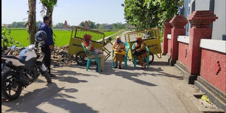 Sejumlah gerobak tempat sampah menutupi jalan keluar masuk desa Tusmi Kulon , yang berbatasan dengan Desa Wotgali Kecamatan Plered Kabupaten Cirebon, (Senin 27/7/2020). Sejumlah perangkat desa duduk dan teus memberikan edukasi dan sosialisasi kepada warga.