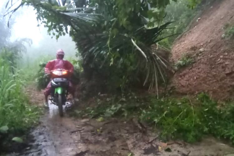 PENGENDARA motor melintas di lokasi tebing longsor yang menimbun badan jalan penghubung antardesa di Jatinunggal, Sumedang, Jawa Barat, Rabu (6/3/2019).