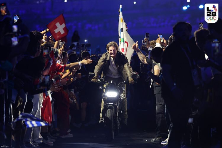 Tom Cruise di atas LiveWire S2 Del Mar yang membawa bendera Olimpiade