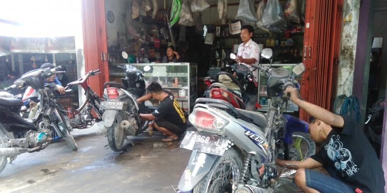 Aktivitas perbaikan sepeda motor yang rusak akibat banjir di bengkel adhi motor, Senin (28/11/2016).
