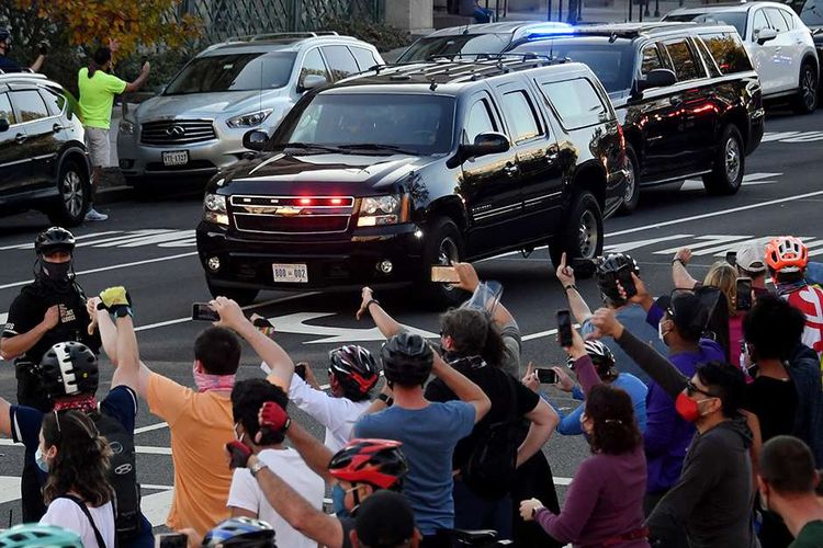 Warga mengolok-olok iringan kendaraan yang membawa Presiden AS Donald Trump dalam perjalanan menuju Gedung Putih, Washington DC, AS, Sabtu (7/11/2020). Joe Biden dipastikan melenggang ke Gedung Putih dengan 290 suara elektoral yang diraihnya sejauh ini, mengakhiri kepemimpinan 4 tahun Donald Trump.