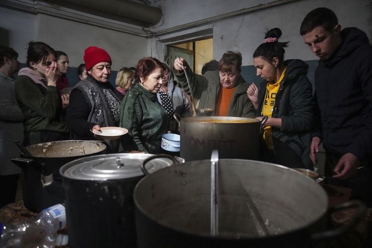 Orang-orang antre untuk menerima makanan panas di tempat perlindungan di Mariupol, Ukraina, Senin, (7/3/2022).