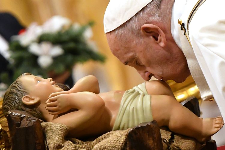 Paus Fransiskus mencium patung Bayi Yesus saat misa Malam Natal di Basilika Santo Petrus, Vatikan, pada 24 Desember 2019.