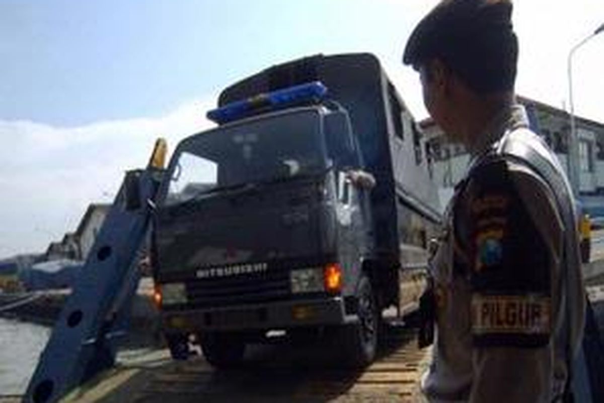 Anggota polres KPPP Tanjung Perak Surabaya mengatur kendaraan pengangkut personel pengamanan coblosan ulang yang masuk ke kapal ferry, Senin (19/1). 