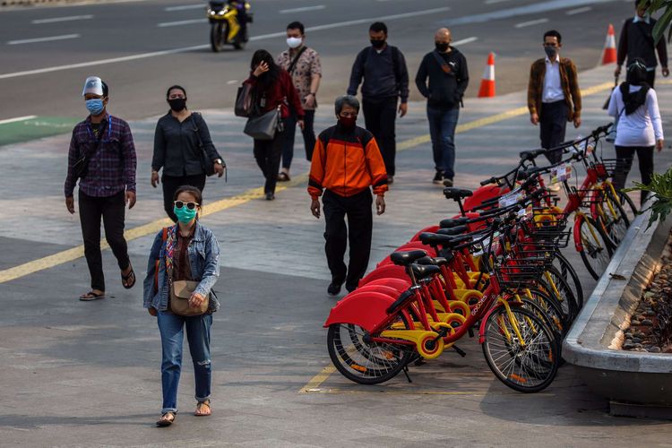 Pekerja yang menggunakan masker saat berjalan menuju kantor masing-masing di Jalan M.H Thamrin, Jakarta Pusat, Senin (14/9/2020). PSBB kembali diterapkan tanggal 14 September 2020, berbagai aktivitas kembali dibatasi yakni aktivitas perkantoran, usaha, transportasi, hingga fasilitas umum.