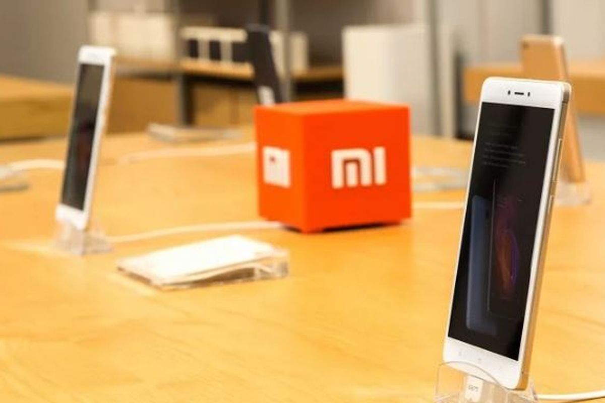 Ilustrasi logo Xiaomi di antara dua ponsel Redmi
