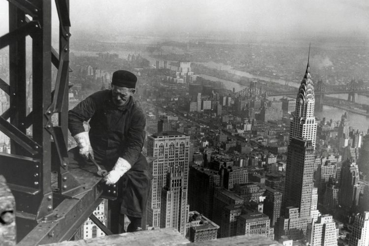 Seorang pekerja sedang berada di lokasi konstruksi The Empire State Building pada tahun 1930. Bangunan tinggi yang ada di sebelah kanan adalah  Chrysler Building
