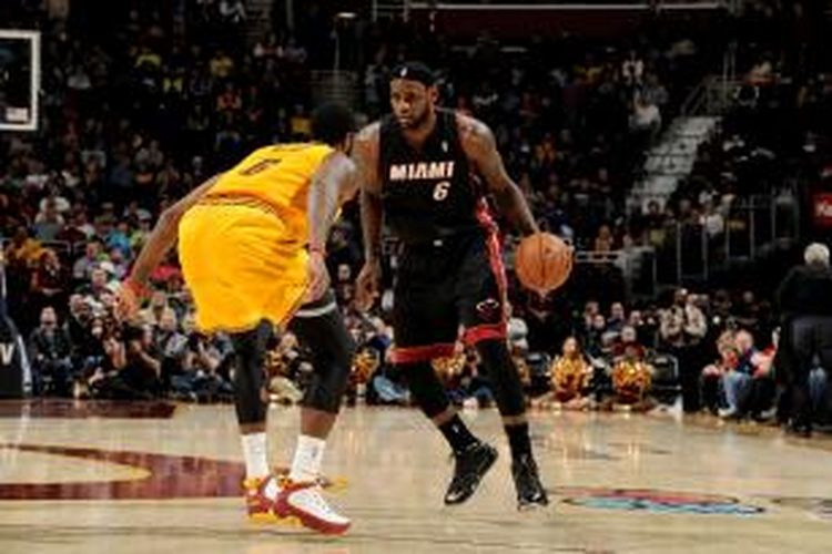 Pebasket Miami Heat, LeBron James (hitam) mencoba melewati pemain Cleveland Cavaliers, pada laga lanjutan kompetisi NBA di The Quicken Loans Arena, pada Rabu (27/11/2013).