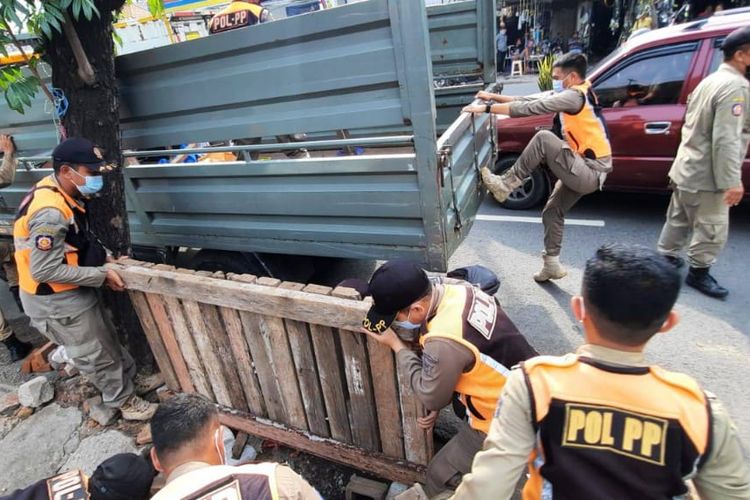 Anggota Satpol PP Surabaya melakukan penertiban PKL di Jalan Gembong Surabaya, Selasa (1/2/2022).