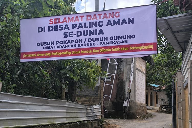 Warga ganti spanduk desa maling menjadi desa paling aman se-dunia di Desa Larangan Badung, Pamekasan, Kamis (21/8/2025)