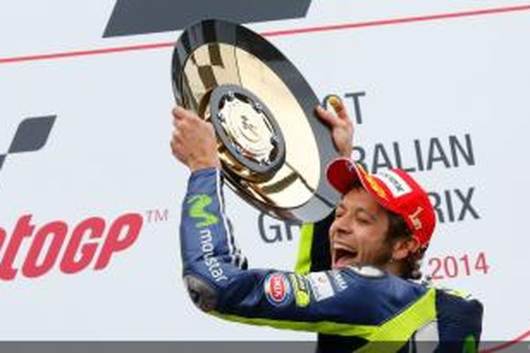 Pebalap Movistar Yamaha asal Italia, Valentino Rossi, mengangkat trofi juara GP Australia di atas podium Sirkuit Phillip Island, Minggu (19/10/2014).