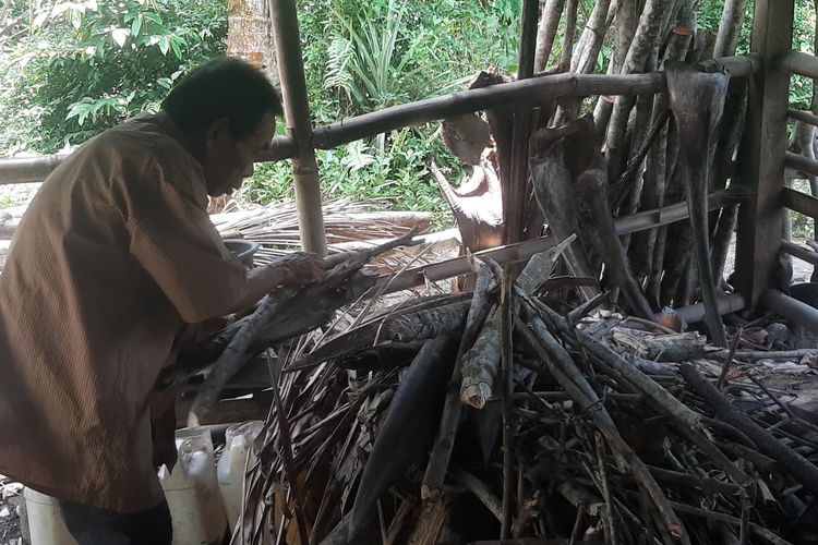 Jumadi menata tumpukan kayu bakar di rumahnya, Sabtu (30/3/2024).