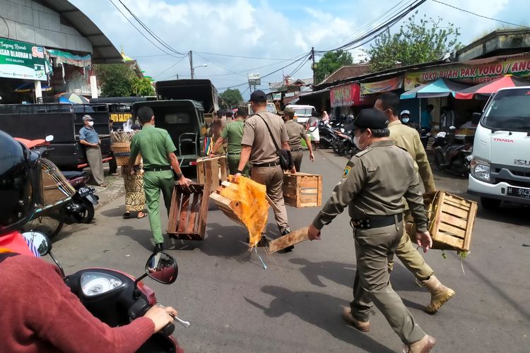 Anggota Satpol PP Kota Salatiga mengangkut kotak buah yang digunakan untuk berjualan di trotoar