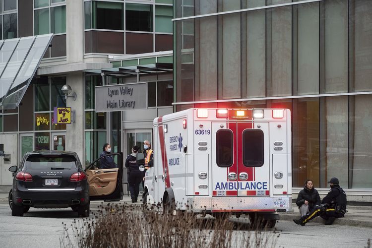 Polisi Kanada berbicara dengan seorang wanita yang duduk di luar Lynn Valley Library, Vancouver utara, British Columbia, pada Sabtu (27/3/2021). Polisi mengatakan, beberapa korban ditusuk di dalam dan luar perpustakaan.