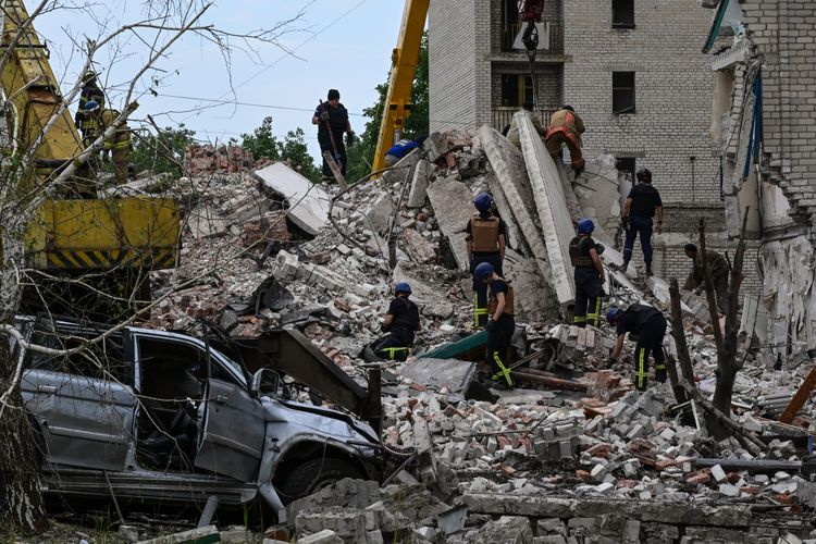Tim penyelamat membersihkan tempat kejadian setelah sebuah bangunan hancur sebagian akibat serangan rudal Rusia di sebuah bangunan perumahan empat lantai di Chasiv Yar, Distrik Bakhmut, Ukraina timur, pada 10 Juli 2022.