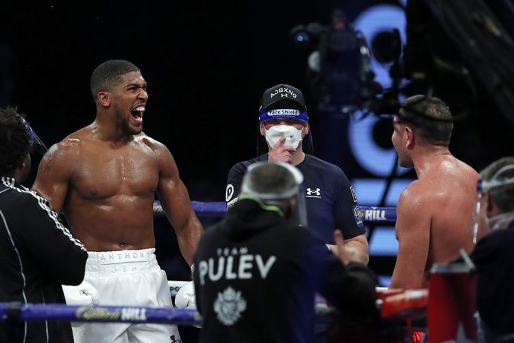 Petinju asal Inggris, Anthony Joshua (kiri), merayakan kemenangan atas penantang dari Bulgaria, Kubrat Pulev (kanan), pada duel kelas berat di The SSE Arena, London, Inggris, Minggu (13/12/2020) pagi WIB.