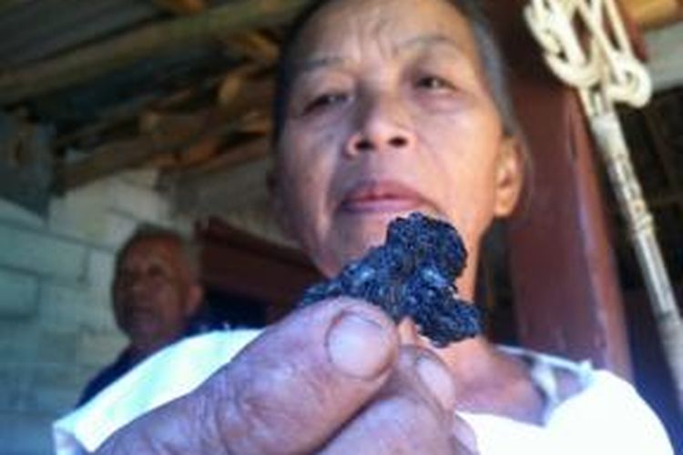 Murbiah, istri sunarmo saat menujukan beras yang dicurigai mwngumpal dan lengket seperti plastik saat usai dibakar api.