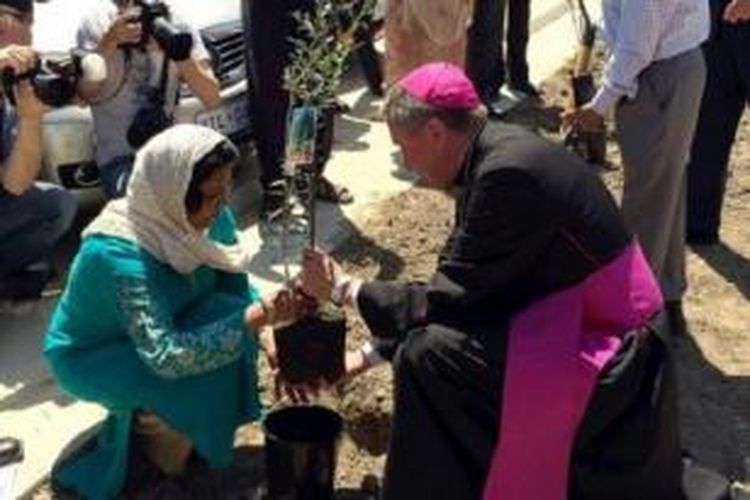 Uskup Agung Christopher Prowse dan Azra Khan dari Islamic Center Canberra menanam pohon zaitun bersama di Universitas Monash