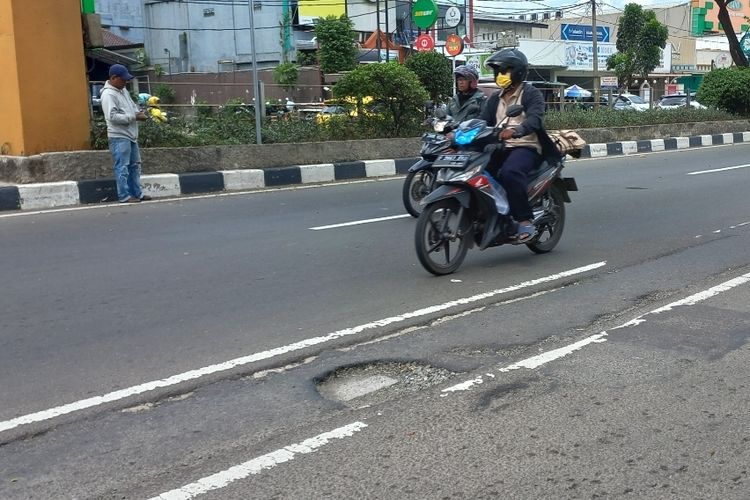 Pengendara motor melintasi jalan berlubang