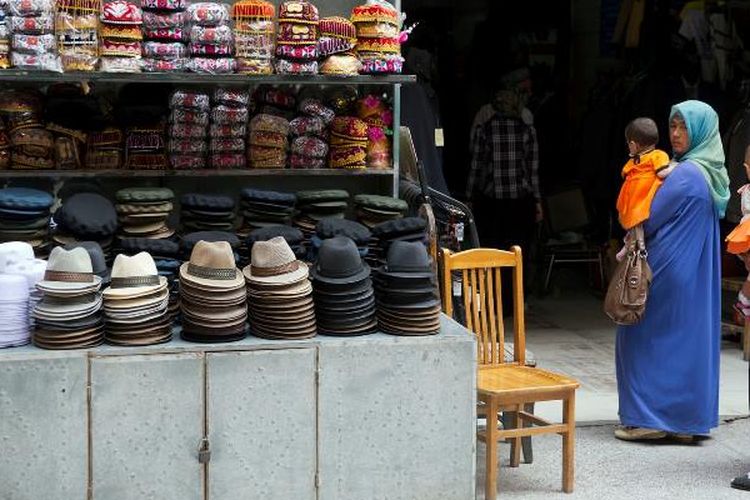 Perempuan suku Uighur mengunjungi sebuah pasar di kota Aksu di provinsi Xinjiang, China barat. (AP via The Guardian)