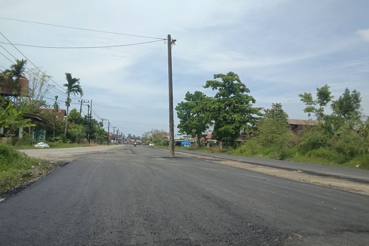 Sebuah tiang listrik berada di tengah proyek Jalan Raya Kurao, Padang.