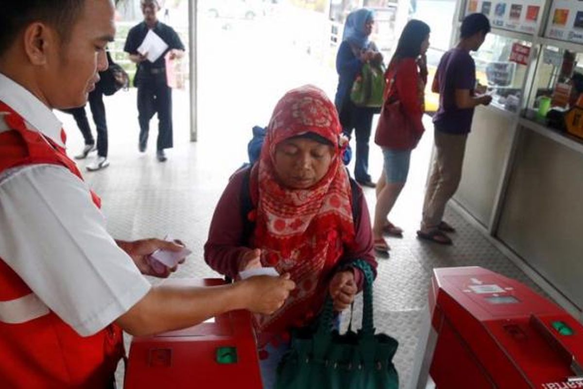 Petugas berjaga menerima tiket kertas di depan mesin  tiket elektronik yang belum beroperasi di Terminal Kalideres, Jakarta, Minggu ( 7/4/2013). Mulai Mei 2013, semua koridor transjakarta berencana akan menggunakan tiket elektronik (e-ticketing) dan sstem tiket manual akan dihilangkan. 

