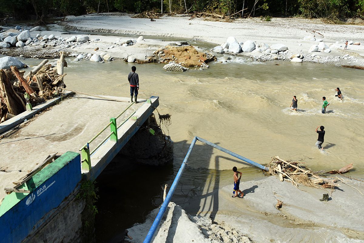 Pengungsi menyeberangi sungai di Desa Kamiri Masamba, Kabupaten Luwu Utara, Sulawesi Selatan, Selasa (21/7/2020). Warga di daerah tersebut terpaksa menyeberangi sungai untuk mengambil bantuan karena jembatan penghubung desa mereka terputus akibat diterjang banding bandang.