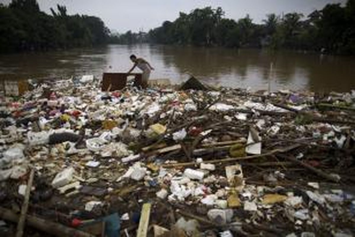 Pemulung mengangkat pintu di atas sampah yang menumpuk akibat luapan Kali Ciliwung di Tebet, Jakarta Selatan, Senin (13/1/2014). Luapan Kali Ciliwung mulai menggenangi permukiman dan memutus Jalan KH Abdullah Syafi'ie sejak Senin dini hari. KOMPAS/AGUS SUSANTO