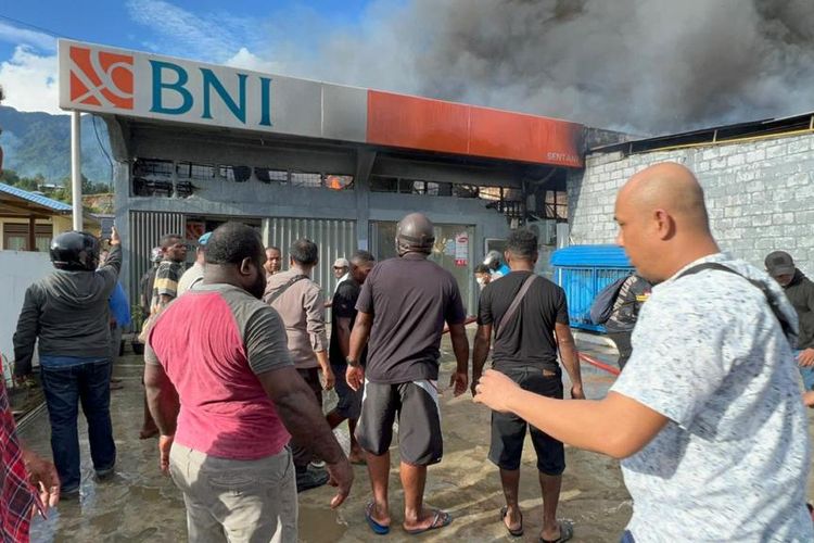 Pihak pemadam kebakaran bersama kepolisian dan warga sekitar, saat berusaha melakukan pemadaman api yang menjalar ke Kantor Cabang BNI Sentani, Kabupaten Jayapura, Papua, Senin (02/05/2022).