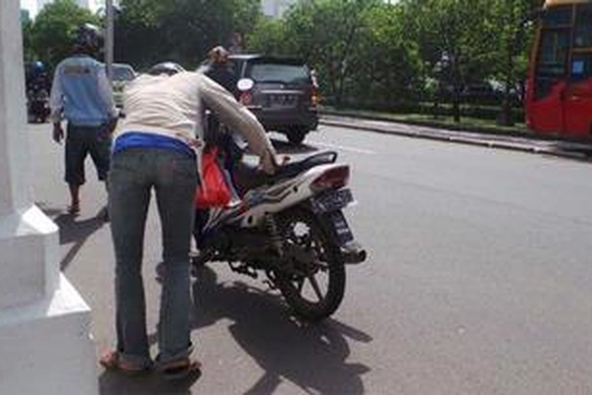 Seorang pengendara tengah memeriksa kendaraannya yang terkena ranjau paku di depan Istana Negara, Jakarta, Selasa (9/4/2013).