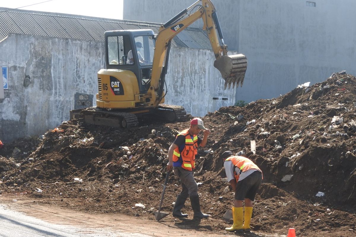 Petugas dari DPUPRPKP Kota Malang melakukan pembersihan tumpukan sampah yang menggunung dan meluber ke jalan di lahan kosong yang berada di Jalan Puntodewo, Kota Malang, Jawa Timur. 