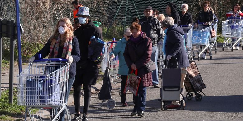 Para pengunjung mengantre di luar supermarket sebelum pemerintah Belgia menerapkan lockdown untuk melawan virus corona pada 18 Maret 2020 siang waktu setempat.