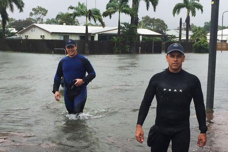 Foto yang dirilis Kantor Kepolisian Queensland memperlihatkan dua petugas polisi di tengah ruas jalan yang tergenang banjir hingga menjadi bak sungai di Kota Townsville, pada Sabtu (2/2/2019).