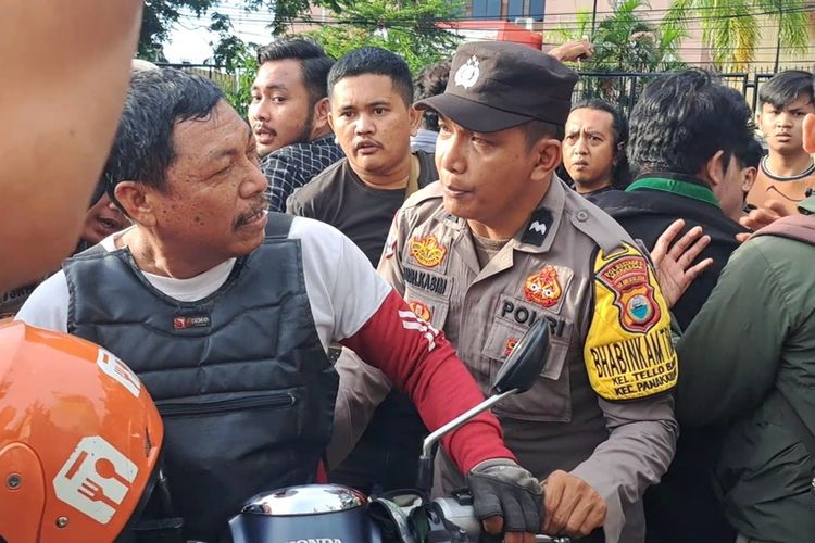Maskur, salah seorang pengendara ojek online berusaha diamankan oleh polisi saat dirinya nyaris jadi bulan-bulanan sejumlah mahasiswa yang menggelar aksi penolakan pengesahan Perppu UU Cipta Kerja di Kota Makassar Sulawesi Selatan (Sulsel), Senin (3/4/2023).