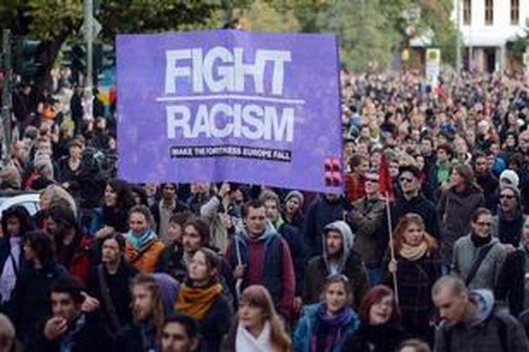 Beberapa demonstran menghamparkan spanduk "Fight Racism" sebagai bagian dari gerakan dari Refugee Protest March di Berlin, Jerman, Sabtu (13/10/2012). Lebih dari 3.000 pendatang dan pendukung gerakan itu berjalan mengelilingi sejumlah jalanan Berlin untuk memperjuangkan hak para pencari suaka. Mereka berbaris mulai dari Wuerzburg, Bavaria pada September 2012, melintasi Jerman dan berakhir di depan gedung Parlemen Federal (Bundestag).