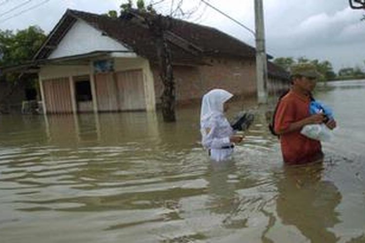Warga melintasi jalan yang terendam banjir Sungai Bengawan Solo di Desa Piyak, Kecamatan Kanor, Bojonegoro, Jawa Timur, Senin (18/2/2013). Banjir yang mencapai ketinggian satu meter tersebut memutus jalan yang menghubungkan antara kecamatan Kanor dengan dengan Kecamatan Sumberejo. 
