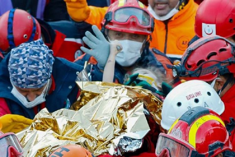 Elif Perincek, bocah tiga tahun yang diselamatkan dari reruntuhan bangunan di Izmir, Turki, memegang jempol pemadam kebakaran yang menyelamatkannya. Setidaknya 87 orang tewas dalam gempa Turki yang terjadi Jumat (30/10/2020).