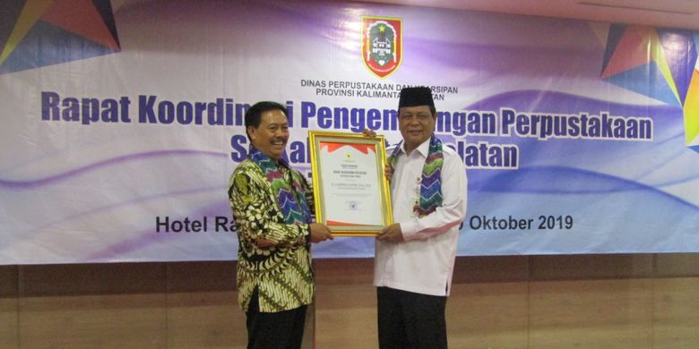 Kepala Perpustakaan Nasional RI Muhammad Syarif Bando memberikan Kepala Perpustakaan Nasional RI Muhammad Syarif Bando memberikan penghargaan Nugra Jasadarma Pustaloka kepada Gubernur Kalimantan Selatan H Sahbirin Noor di Hotel Rattan Inn Banjarmasin, Rabu (9/10).
 kepada Gubernur Kalimantan Selatan, Sahbirin Noor di Hotel Rattan Inn Banjarmasin, Rabu (9/10/2019).
