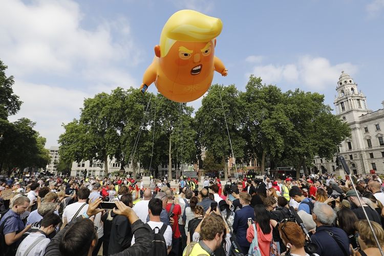 Warga London beserta para aktivis mengabadikan balon bayi Trump raksasa saat diterbangkan di tengah aksi demonstrasi memprotes kunjungan Presiden AS ke Inggris, Jumat (13/7/2018).