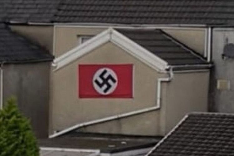 Bendera simbol swastika dipasang di tembok bagian belakang sebuah rumah bertingkat di Wales.