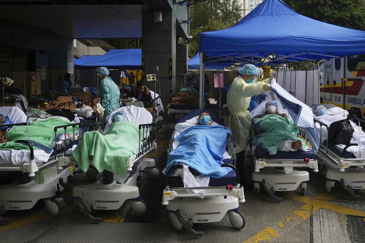 Pasien berbaring di ranjang rumah sakit saat mereka menunggu di area perawatan sementara di luar Caritas Medical Center di Hong Kong, Jumat, 18 Februari 2022. 