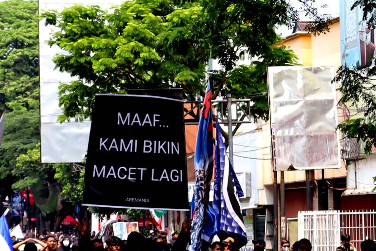 Salah satu peserta dari suporter Arema, Aremania dan masyarakat membawa poster permintaan maaf atas aksi damai terkait Tragedi Kanjuruhan untuk menuntut keadilan yang dilaksanakan di sejumlah titik Kota Malang, Minggu (04/12/2022) siang.