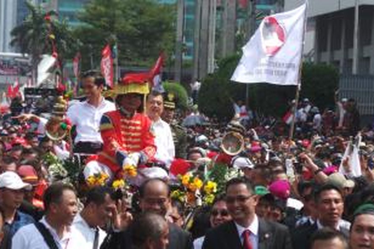 Presiden Joko Widodo dan Wakil Presiden Jusuf Kalla saat menumpang kereta kencana di Jalan MH Thamrin, Jakarta. Senin (20/10/2014).