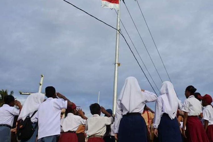 Para pelajar di Kecamatan Aru Tengah, Kabupaten Kepulauan Aru, Maluku menghormati bendera merah putih yang dipasang di tiang listrik seusai mengikuti upacara HUT Proklamai kemerdekaan RI ke-74 di wilayah tersebut, Sabtu (17/8/2019)