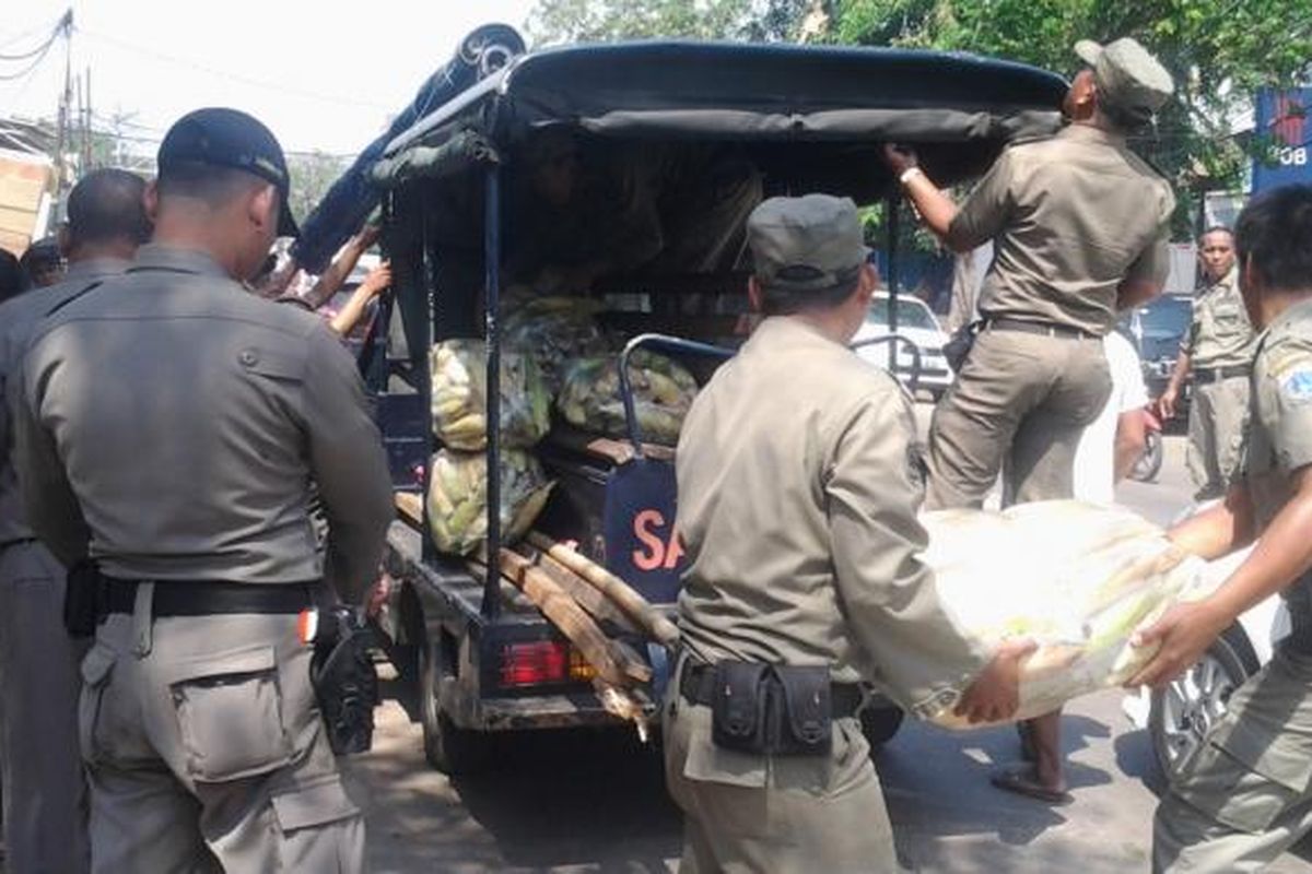 Petugas Satpol PP Jakarta Barat menertibkan barang-barang pedagang kaki lima (PKL) yang berjualan di badan Jalan KH Moh Mansyur, Tambora, Jakarta Barat, Selasa (15/7/2014).