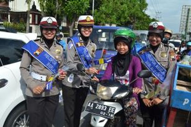 Para Polwan Polres Magelang membagikan helm dan bunga gratis untuk pengendara sepeda motor perempuan di Kota Magelang untuk memperingati Hari Ibu, Selasa (22/12/2015).