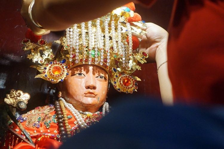 Pengurus memasangkan mahkota di kepala Dewa Mak Co saat ritual memandikan dan mengganti pakaian 17 dewa di Klenteng Tjoe Tik Kiong, Tulungagung, Jawa Timur, Minggu (23/1/2022). Kegiatan itu digelar sebagai rangkaian menyambut Hari Raya Imlek yang menandai Tahun Baru China pada 1 Februari 2022. 