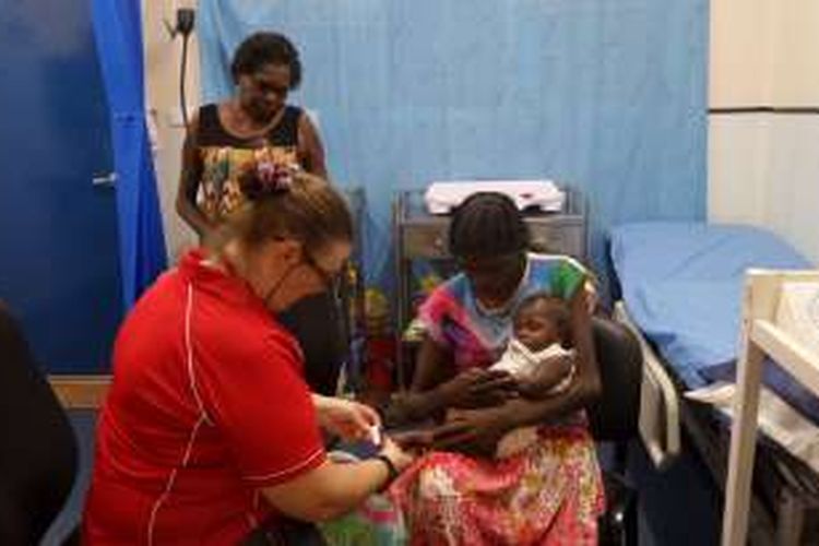 Cynthia Anderson, Child and Family Health Nurse dari Yirrkala Clinic, (kiri) memeriksa bayi Malisha yang dibawa oleh neneknya (berdiri) dan ibunya, Trish Maymuru. Bayi Malisha dibawa ke klinik karena agak sesak ketika bernafas.