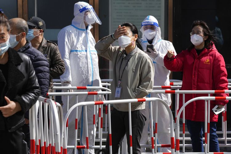 Pekerja berbaris untuk tes COVID di luar gedung kantor pada Senin, 14 Maret 2022, di Beijing. 