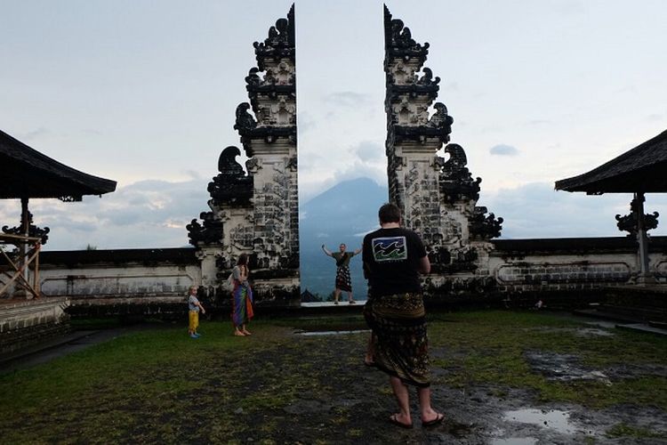 Turis berfoto dengan latar Gunung Agung dilihat dari Pura Lempuyang Luhur, Karangasem, Bali.